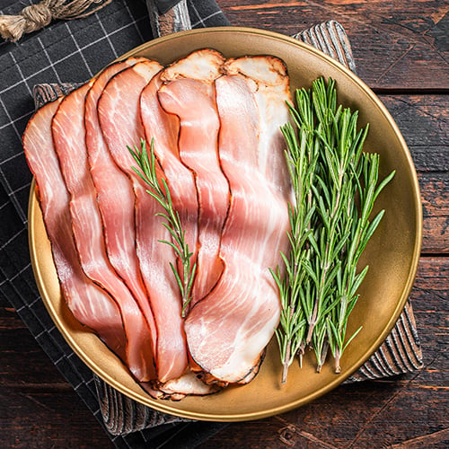 Dry cured Black Forest Ham with rosemary on a wooden background