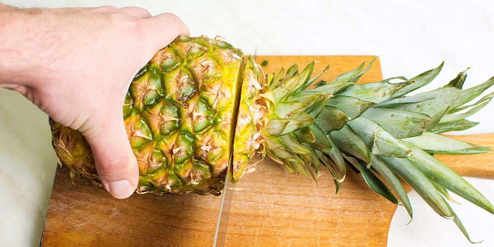 Step Two - Using a large knife, remove the top of the pineapple