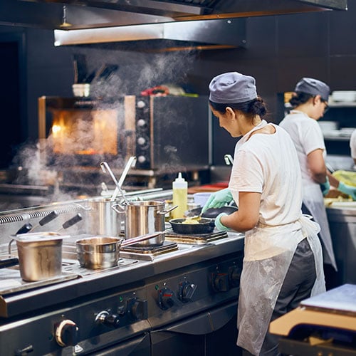 Chef work hours, Dark commercial kitchen with 2 female chefs cooking