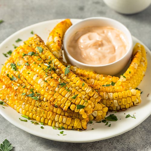Corn Ribs on a white plate with sauce