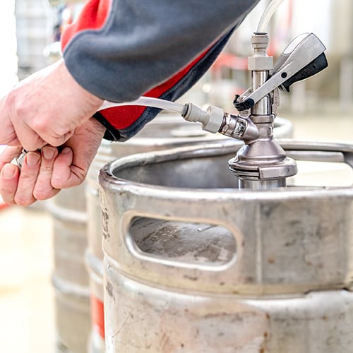 Someone demonstrating how to tap a keg