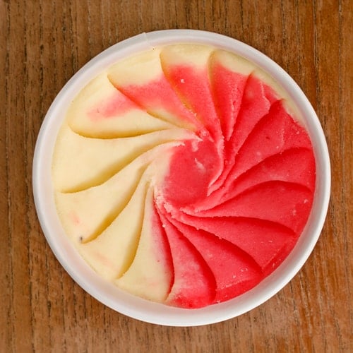 overhead shot of a cup of mixed pink and white italian ice on a wood table