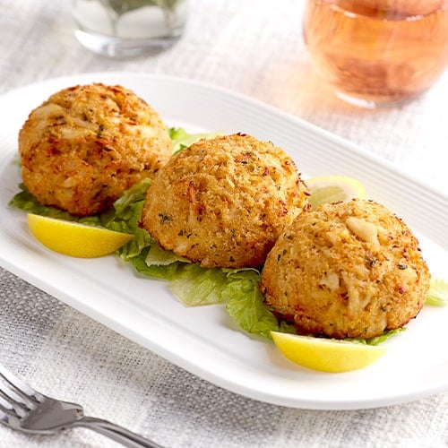 three small crab cakes served on a white plate