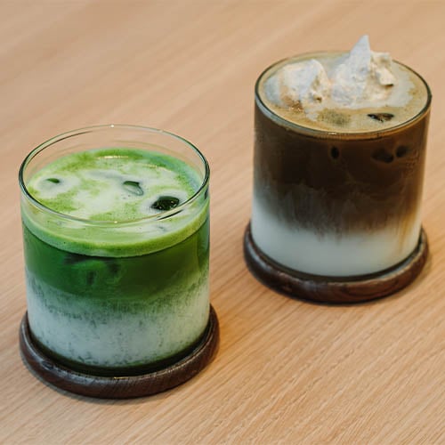 Iced Matcha and Hojicha Latte in Glass Cups on wood surface