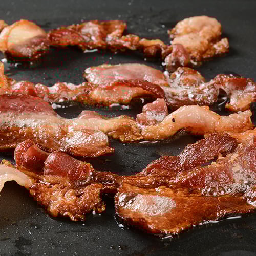 close up of sizzling bacon in a pan