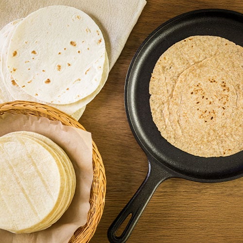 Top view of different types of tortillas on a wooden table
