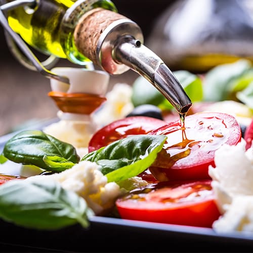 Closeup of oilve oil pouring onto a salad