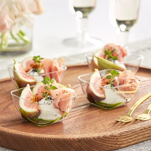 close up transparent tasting cup with fresh fruit, meat and cheese