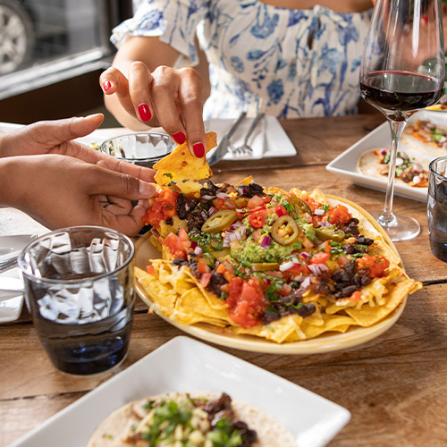 Bowl of nachos with one chip being picked up