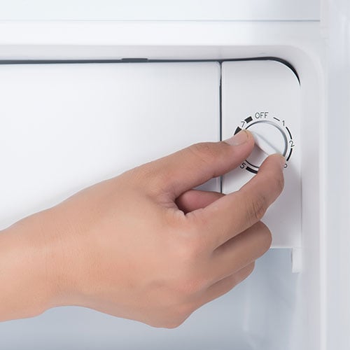 Someone adjusting a refrigerator thermostat