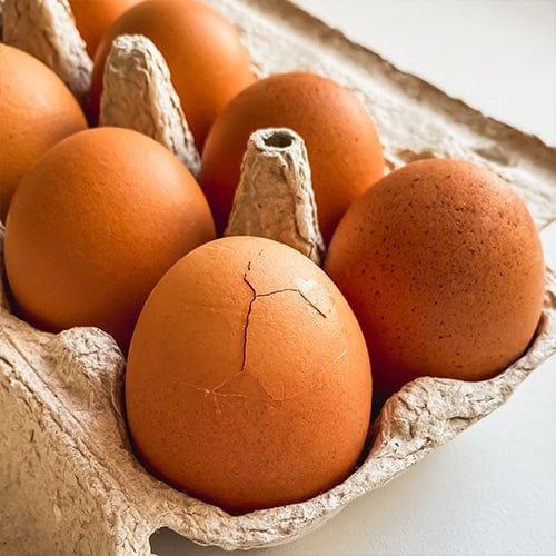 Eggs in an egg carton with one cracked egg