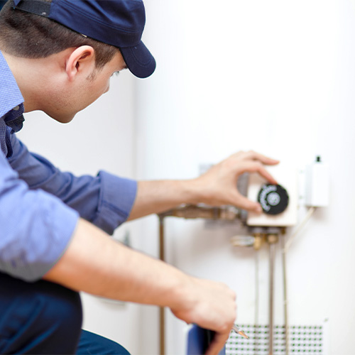 techician adjusting the thermostat on a water heater