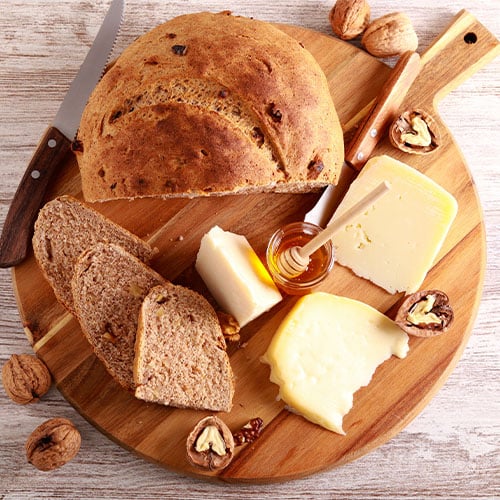 different types of bread and sliced cheese on a charcuterie board