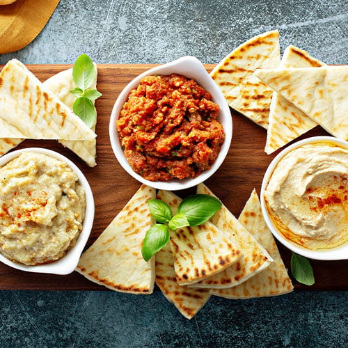 three different dips with pita bread slices beside them