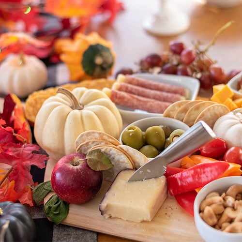 a fall themed charcuterie board with pumpkins and leaves