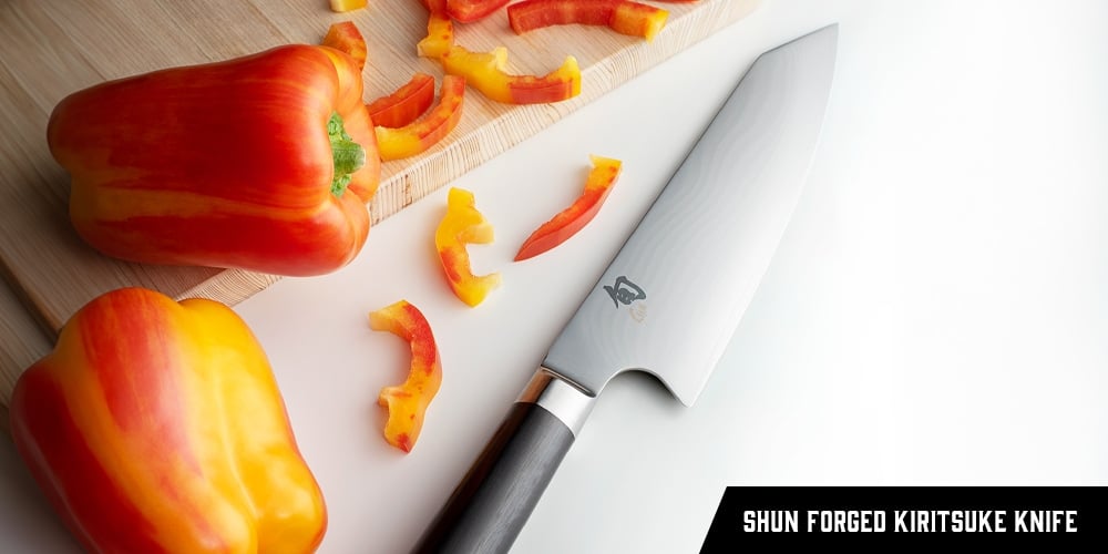 A Shun Classic Forged Kiritsuke Knife lying beside chopped peppers