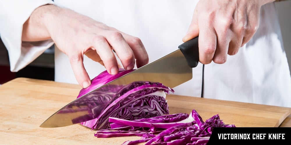 A chef using a Victorinox Chef Knife to cut cabbage