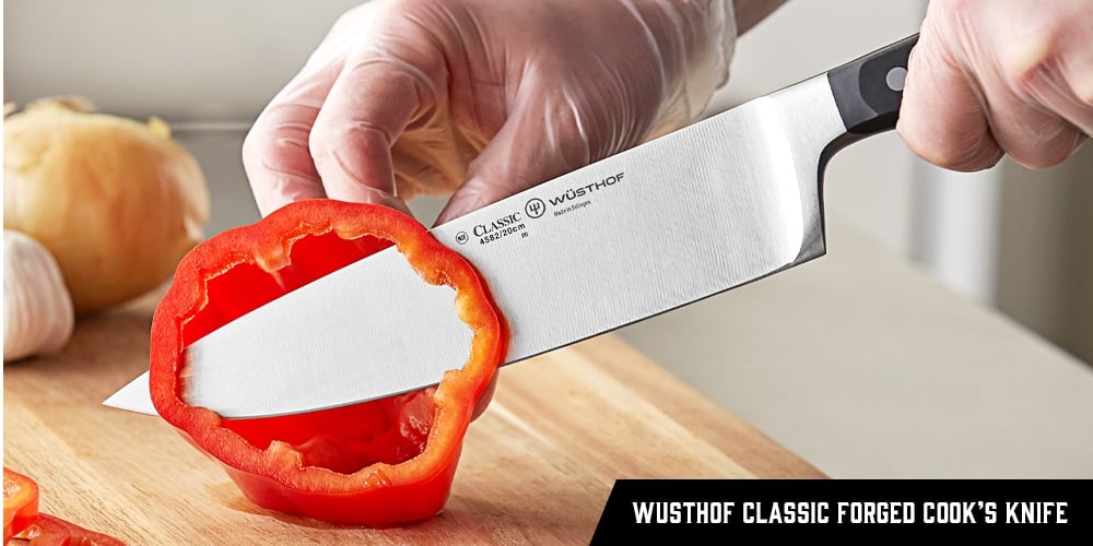 A chef using a Wusthof Classic Forged Cook's Knife to chop a red pepper