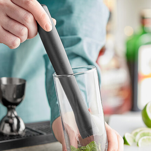 Person using a muddle in a cocktail