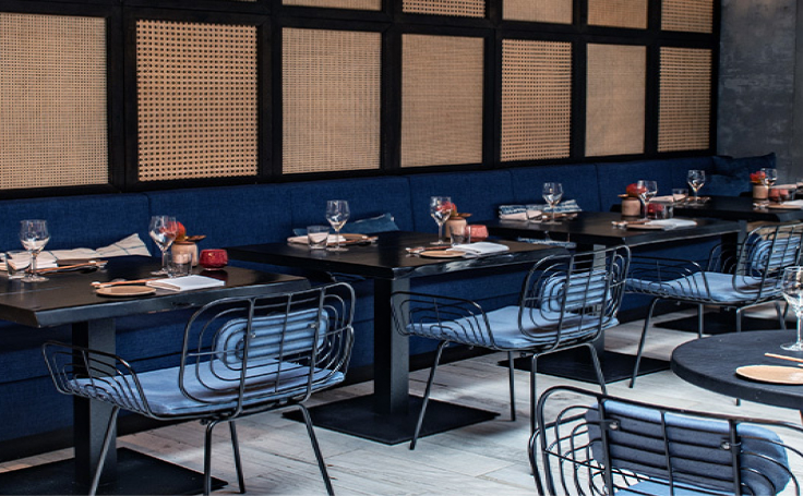 picture of restaurant with black tables and chairs with blue cushions