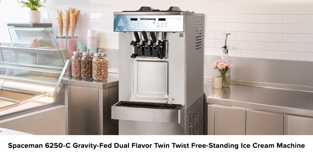 Spaceman 6250-C free-standing soft serve machine in a clean ice cream shop beside a refrigerated display case and jars of toppings.