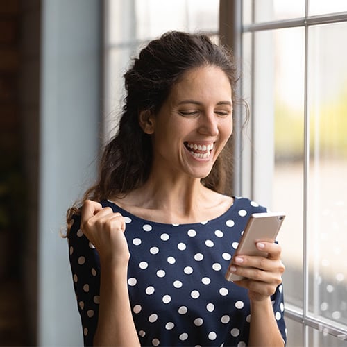 woman celebrating winning a giveaway on her phone