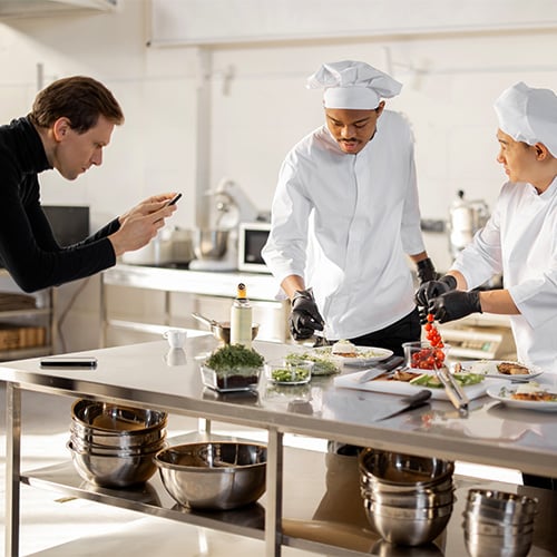 a cameraman filming two chefs for a step by step cooking video
