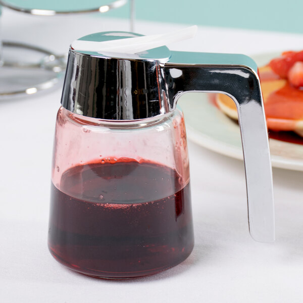 A Tablecraft modern glass syrup dispenser with a red liquid inside and a chrome top.
