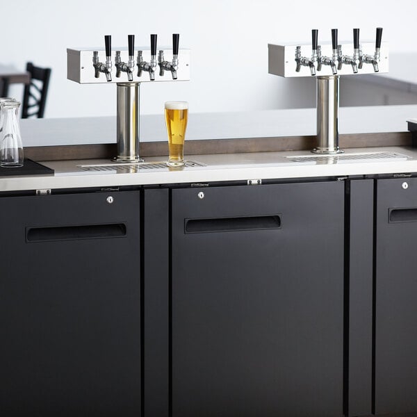 An Avantco black rectangular beer dispenser on a counter with four beer taps.