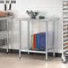 A Steelton stainless steel work table with an undershelf holding different colored cutting boards.
