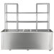 A stainless steel rectangular mobile back bar with glass shelves on wheels.
