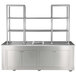 A stainless steel Bon Chef mobile back bar with glass shelves on wheels.