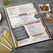 A black Menu Solutions menu board on a table with a fork and knife.
