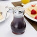 A Tablecraft syrup dispenser filled with syrup on a table with pancakes.
