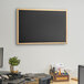 A Dynamic by 360 Office Furniture black wall-mount chalkboard with wood frame.